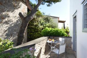 a small garden with a table and chairs on a stone wall at Orloff Resort in Spetses