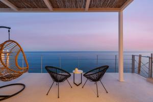a room with chairs and a table and the ocean at Melivia Seafront Resort in Nea Skioni