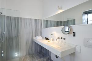 a white bathroom with a sink and a shower at Orloff Resort in Spetses