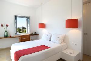 a bedroom with a white bed with red accents at Orloff Resort in Spetses
