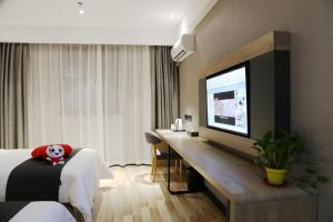 a hotel room with a bed and a desk with a television at Thank Inn Plus Jiangsu Taizhou Renmin Hospital in T'ang-wan-chen
