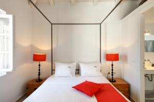 a bedroom with a white bed with red pillows at Orloff Resort in Spetses