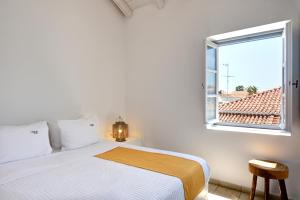a white bedroom with a bed and a window at Orloff Resort in Spetses