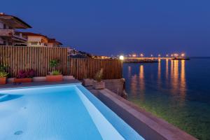 a swimming pool with a view of the ocean at night at Melivia Seafront Resort in Nea Skioni +95 photos