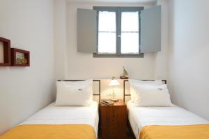 two beds in a room with two windows at Orloff Resort in Spetses