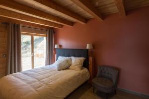 1 dormitorio con 1 cama, 1 silla y 1 ventana en Les chalets perchés, en Muhlbach-sur-Munster