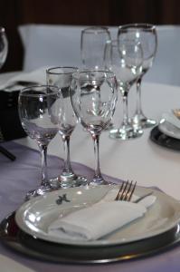 una mesa con un plato y copas de vino. en Río Arriba Suites & Apartments & Restó en Bella Vista
