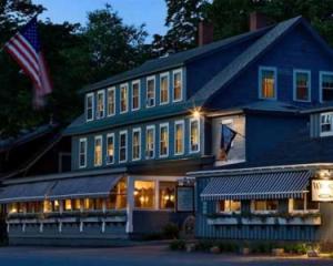 ein großes blaues Haus mit amerikanischer Flagge davor in der Unterkunft Wildcat Inn and Tavern in Jackson