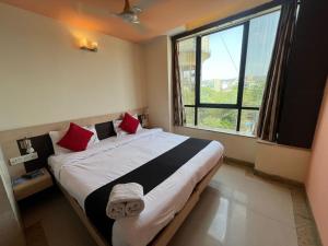 a bedroom with a large bed with red pillows and a window at Hotel Apex Intercontinental in Jaipur