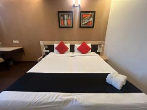 a bedroom with a large white bed with red pillows at Hotel Apex Intercontinental in Jaipur