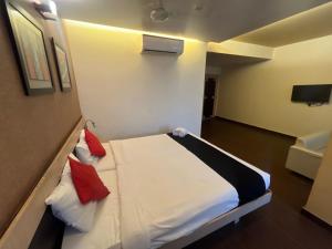 a bedroom with a white bed with red pillows at Hotel Apex Intercontinental in Jaipur