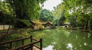 a pond in a garden with a house and trees at Yitel Collection Chengdu Kuanzhai Alley Chutian Junlin in Chengdu