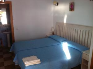 Un dormitorio con una cama azul con toallas. en Hostal Rios, en Bolonia
