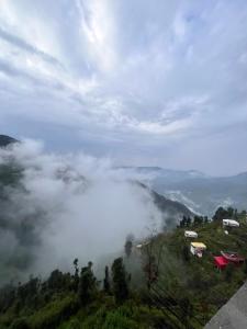 a misty valley in the mountains with houses at M S guest house dhanolti in Dhanaulti +12 photos