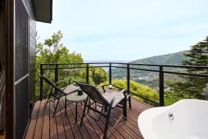 a balcony with two chairs and a bath tub at マイグレChillax in Higashiizu