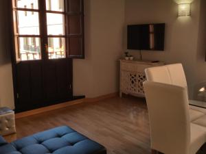 Sala de estar con puerta, sofá y TV en Apartamento Capitania, en Granada