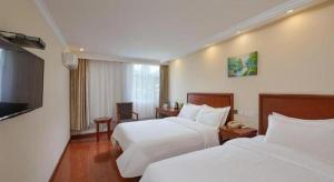 a hotel room with two beds and a flat screen tv at GreenTree Inn Nanjing Forestry University National Exhibition Center Express Hotel in Nanjing