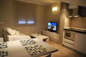 a living room with a couch and a kitchen with a tv at Aparthotel Meseguer in Alcañiz