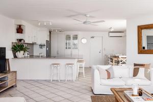 a white living room with a white couch and a kitchen at Hydra - 3 Bedrooms, Ocean views, Pool in Sunshine Beach
