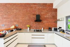a kitchen with white cabinets and a brick wall at ELIVAAS Signature Villa Luxe 3BHK Luxury Retreat with Private Pool & Jacuzzi in Calangute +95 photos