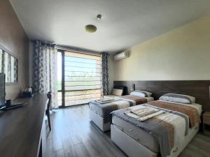 a bedroom with two beds and a large window at Family hotel Delfa in Chernomorets