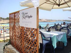 a sign for a restaurant with tables and a beach at Hotel Giglio in Lampedusa