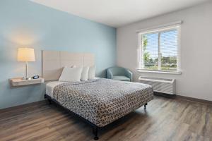 a bedroom with a bed and a chair and a window at WoodSpring Suites Ceres - Modesto in Ceres +19 photos