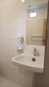 a white bathroom with a sink and a mirror at Bucolic River Resort in Gulmit