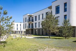 パランガにあるKauko Apartment, TAKAS Į JŪRĄ, Šildomas baseinasの目の前に木々が生い茂るアパートメント