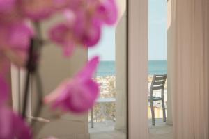 a view of the ocean from a balcony with purple flowers at Hotel Ambassador in Rimini