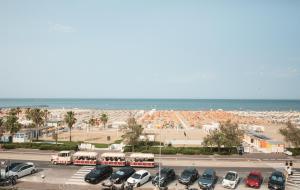 a parking lot with cars and buses in front of the beach at Hotel Ambassador in Rimini