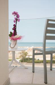 a table with a vase of flowers and a chair at Hotel Ambassador in Rimini