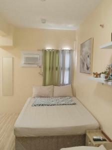 a bedroom with a large bed with a green curtain at A Scandinavian Staycation - ROMA 1616 in Mactan Island