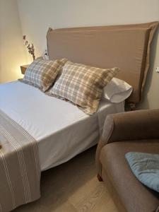 a bedroom with a bed with pillows and a couch at Apartamento Mar de Cruz in Pontevedra