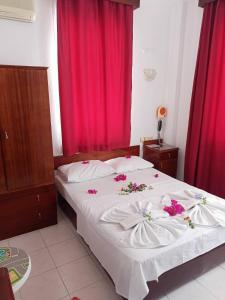 a bedroom with a white bed with flowers on it at Villa Fortin Pension in Kuşadası