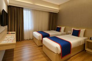 a hotel room with two beds and a television at Zip By Spree Hotels Samudra Belgaum in Belgaum
