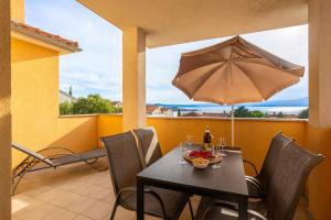 a table with a bowl of fruit and an umbrella at Villa Sbay in Omišalj
