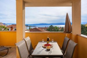 a table with wine glasses and a bowl of fruit on a balcony at Villa Sbay in Omišalj