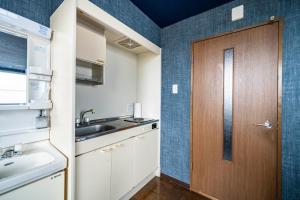 a kitchen with a sink and a wooden door at Silk Court 301 in Chitose