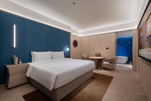 a bedroom with a large bed and a bathroom at Orange Crystal Qingdao Liaoyang West Road Guoxin Sports Center Hotel in Qingdao