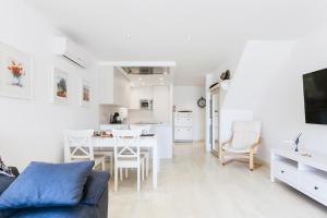 a white living room with a blue couch and a table at Vista Roses Mar - Casa Pescador in Empuriabrava