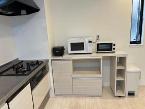 a kitchen with a counter with a microwave and a stove at Tokyo Link House Halona-Direct to Shinjuku, Shibuya, Ginza in Tokyo