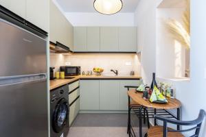 コス・タウンにあるAram's Port Houseのキッチン(白いキャビネット、洗濯機、乾燥機付)