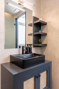コス・タウンにあるAram's Port Houseの黒い洗面台と鏡のあるバスルーム