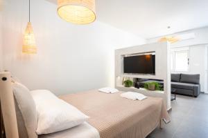 コス・タウンにあるAram's Port Houseのベッドとテレビのある白い部屋