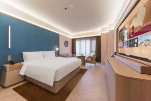 a hotel room with a bed and a flat screen tv at Orange Crystal Qingdao Taitung Pedestrian Street Hotel in Qingdao +11 photos
