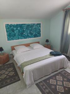 a bedroom with a large white bed with a painting on the wall at Apartament vila Roma in Eforie Nord