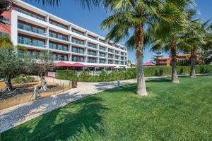 un grand bâtiment avec des palmiers devant lui dans l'établissement Areias Village Beach Suite Hotel, à Albufeira