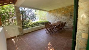a patio with a table and chairs and a stone wall at Villa Maslinica in Maslinica