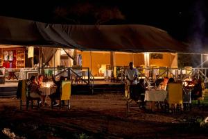 a man standing in front of a tent at night at Pamoja Serengeti Luxury Camp in Serengeti National Park